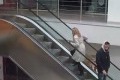 Kvinna går uppför en rulltrappa andra åker ned